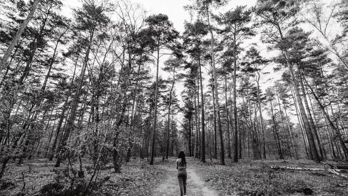 Woman walking on a forest path in Berlin, Germany in black and white.